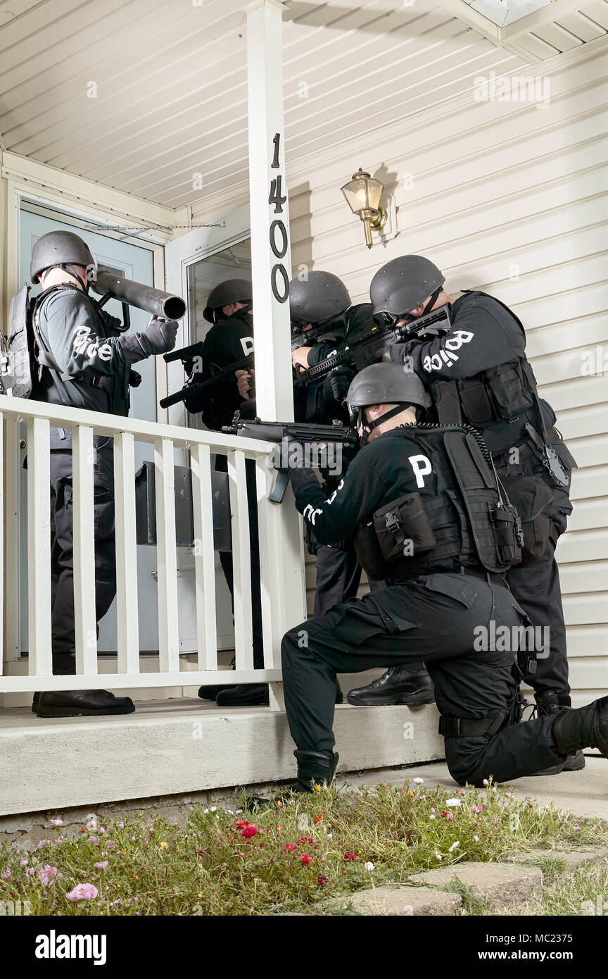 Police tactical or swat team gathered round the door of a house with