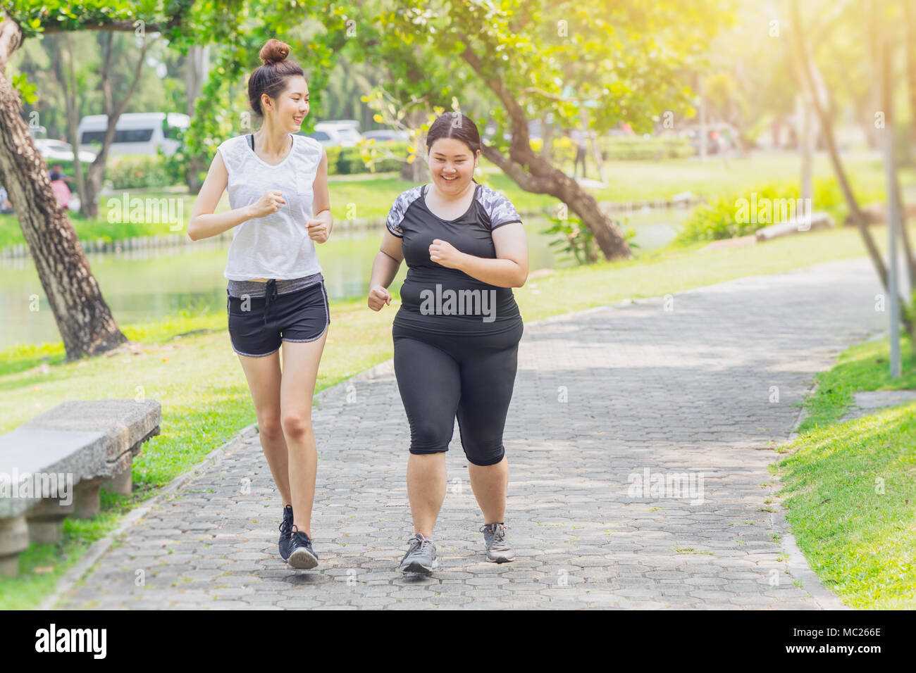 Asian teen running fat and thin friendship jogging in the Park Stock Photo
