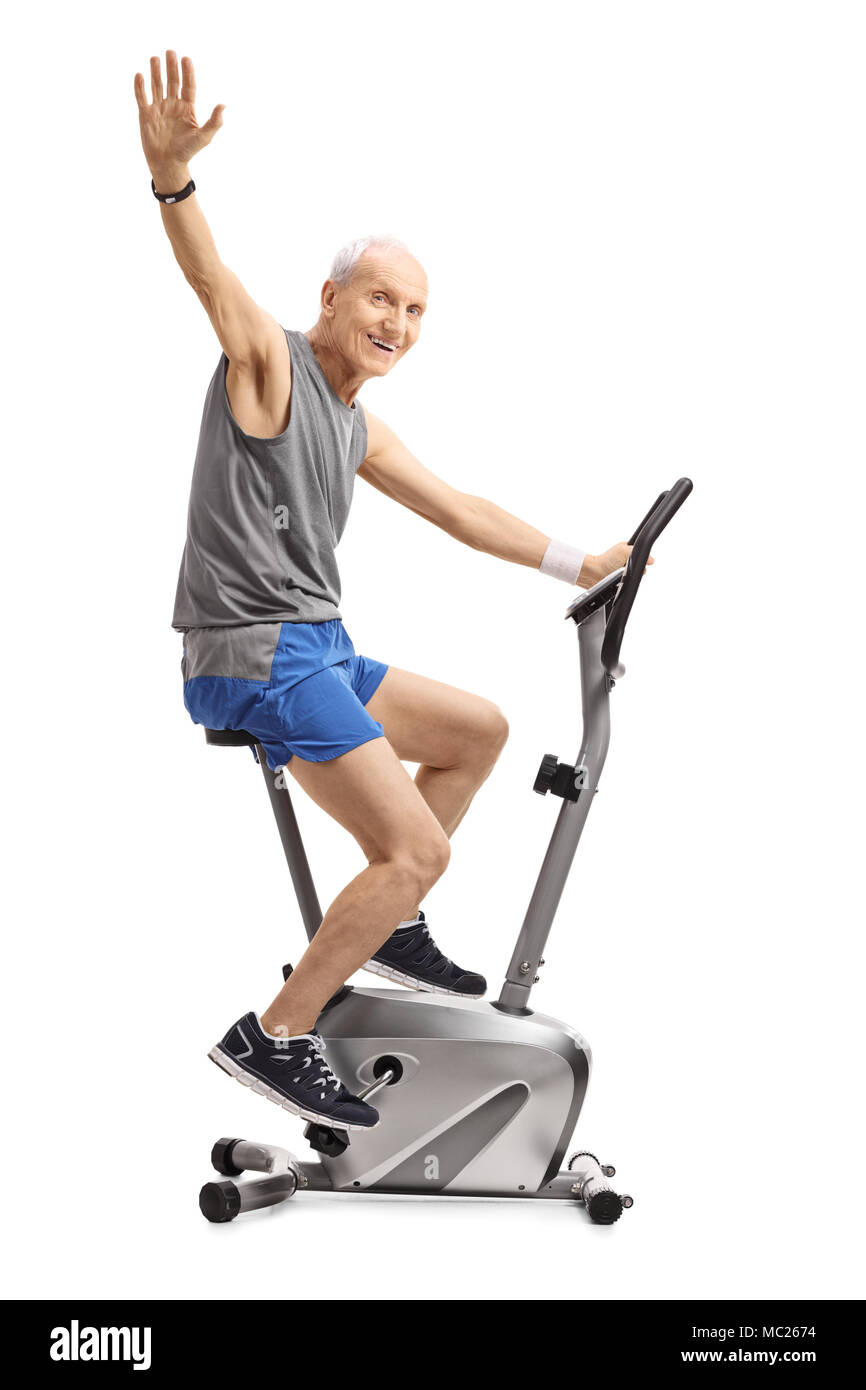 Elderly man exercising on a stationary bike and waving at the camera isolated on white background Stock Photo Alamy