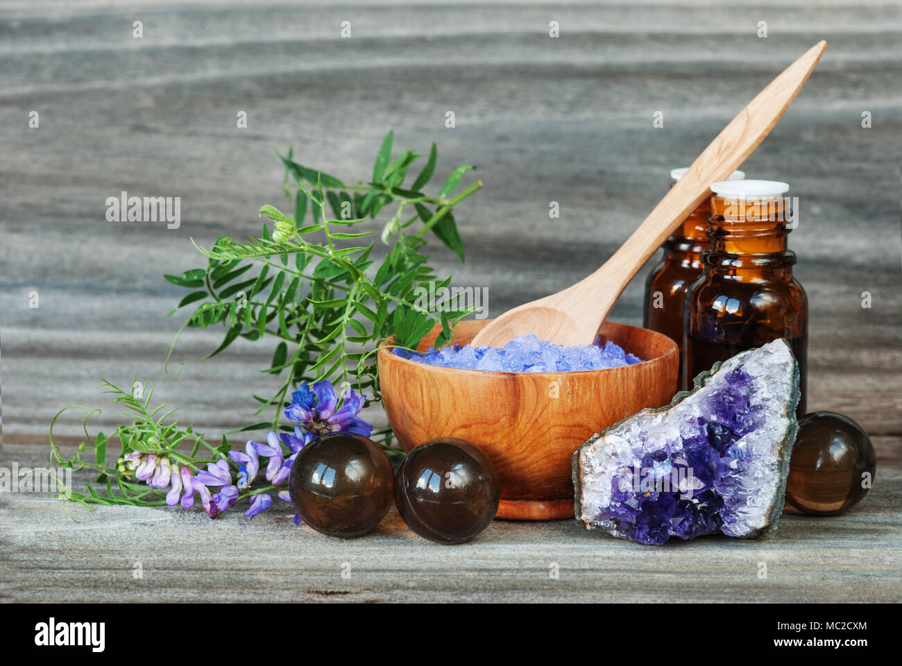 Spa concept. Salt for baths, bottles with essential oils, stone amesist and blue flowers on an old wooden background Stock Photo