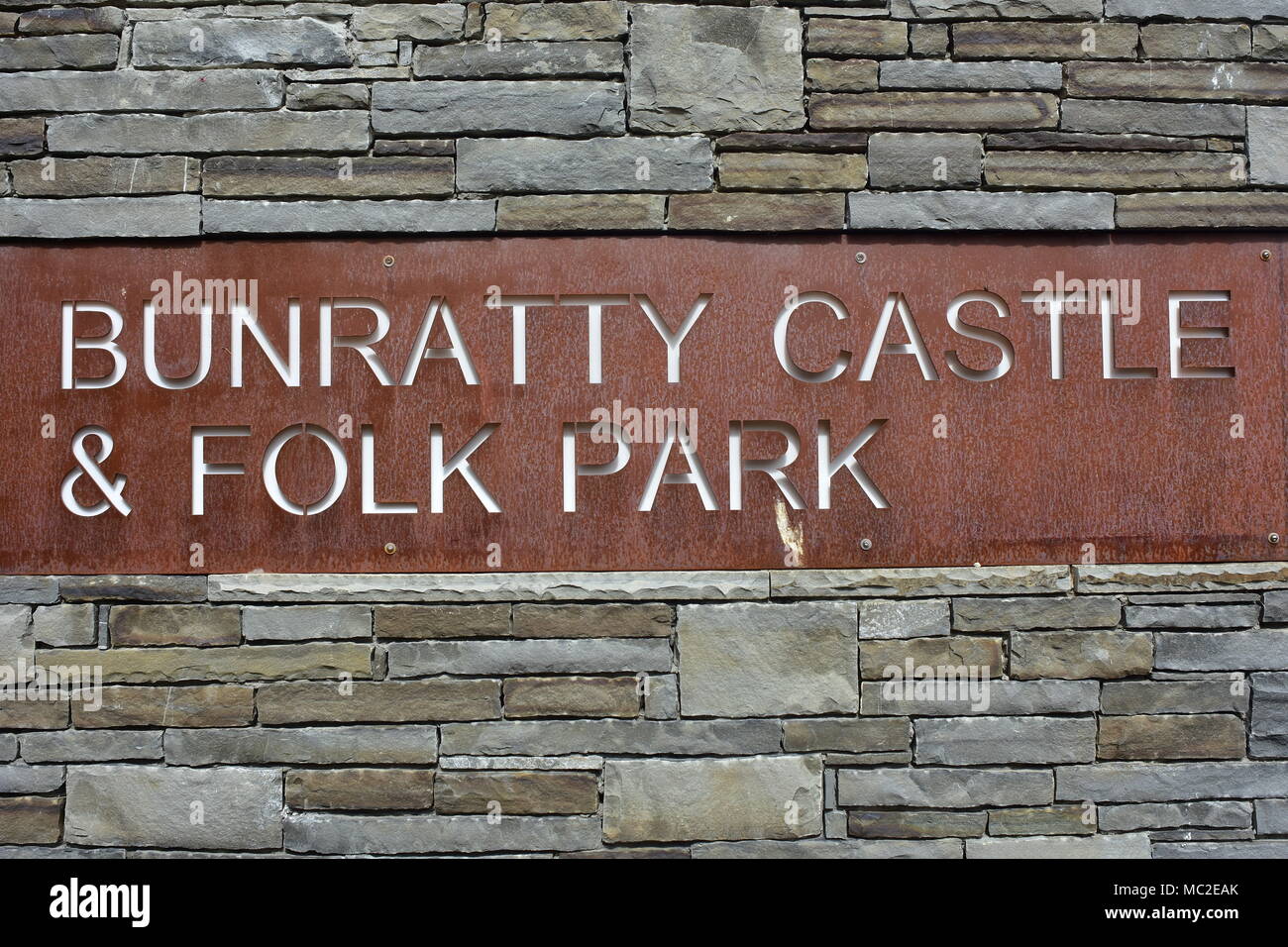 Bunratty Castle and folk park sign made from surface rusty steel sheet on gray slated wall. Stock Photo