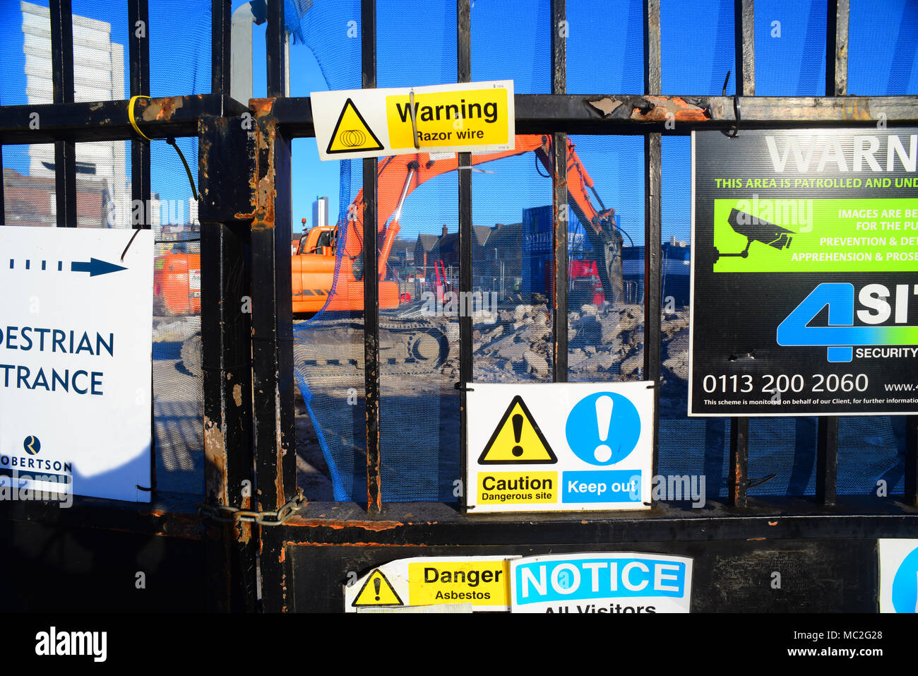 hammer drill working by health and safety warning signs on gate of