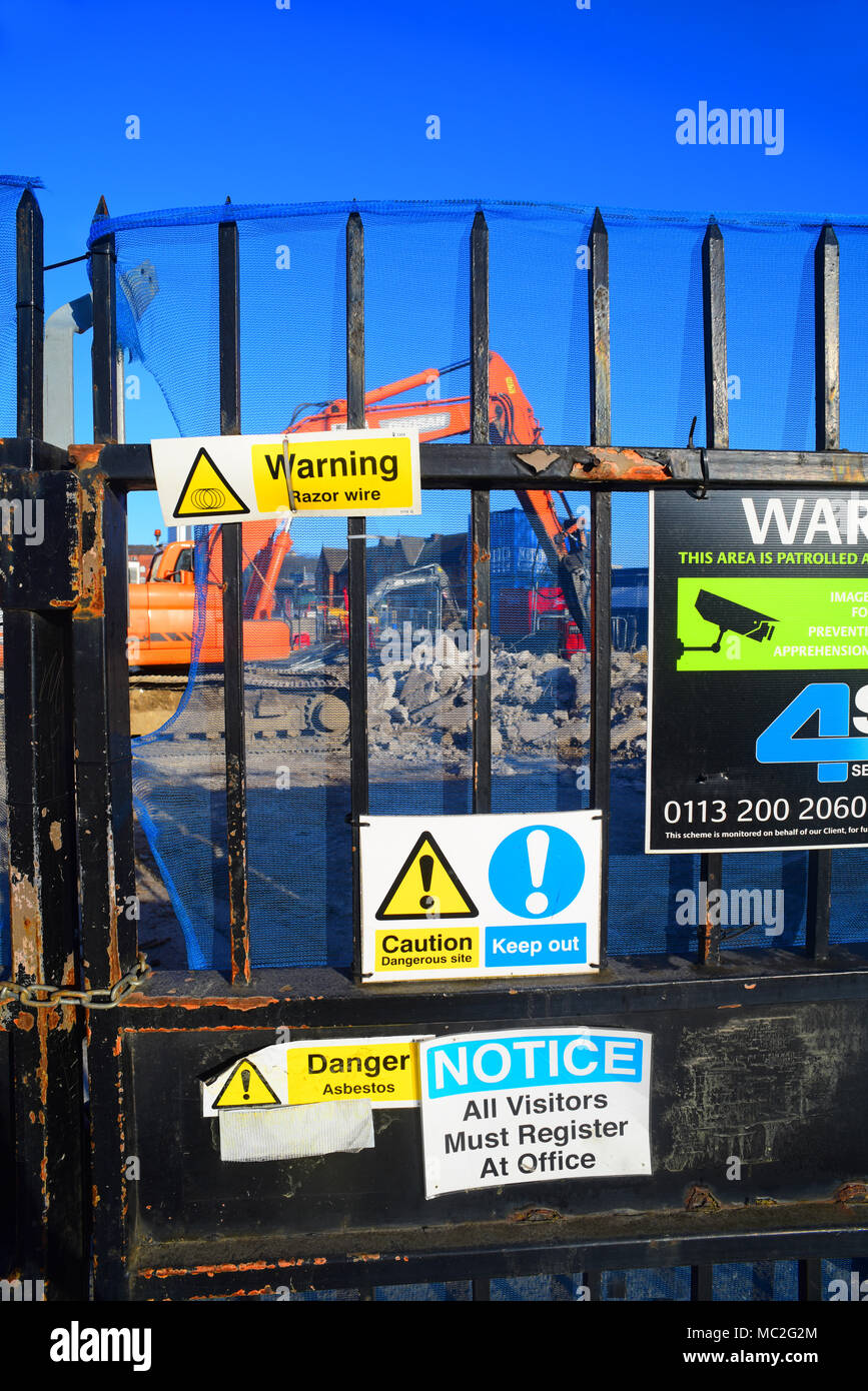 hammer drill working by health and safety warning signs on gate of