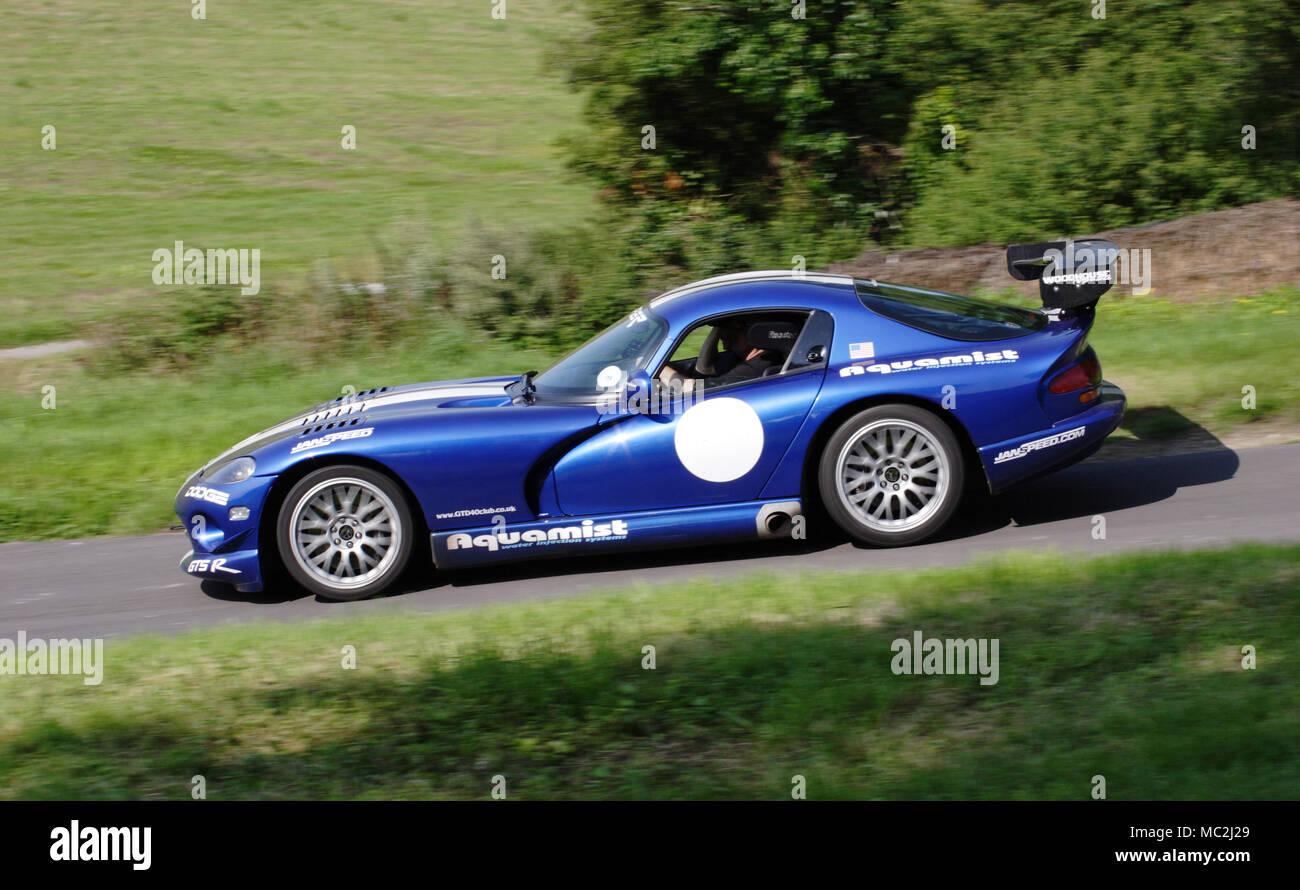 Blue Dodge Viper in profile (side view) driving fast on a country road. Stock Photo