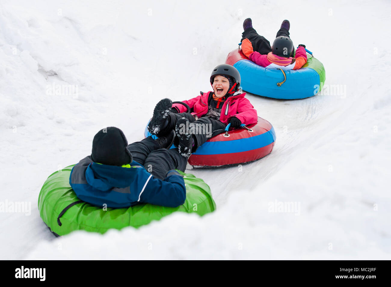 Kids on snow tubes downhill at winter day Stock Photo