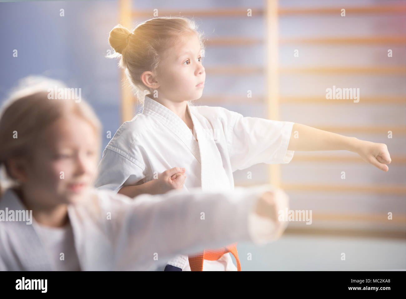 Girl in white kimono practicing karate during extra-curricular class at school Stock Photo