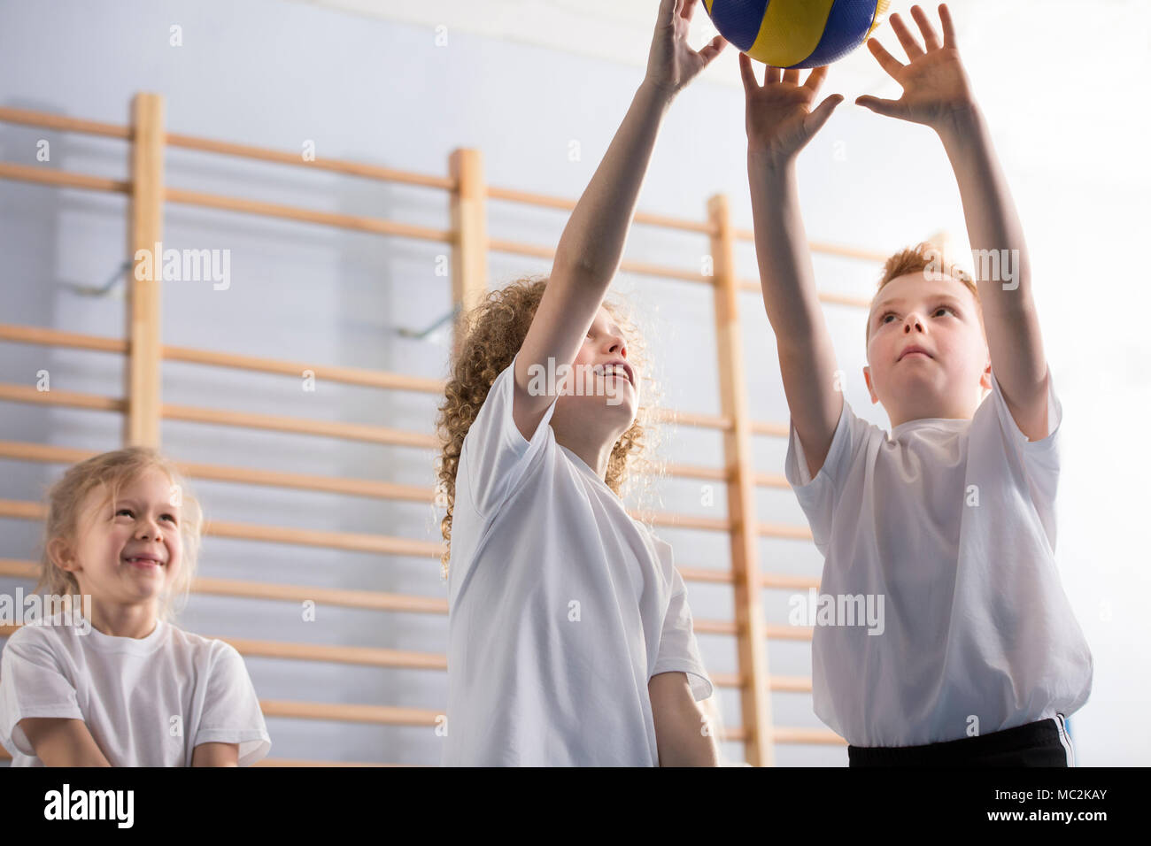 Low angle of happy boys playing volleyball during sports activities at school Stock Photo