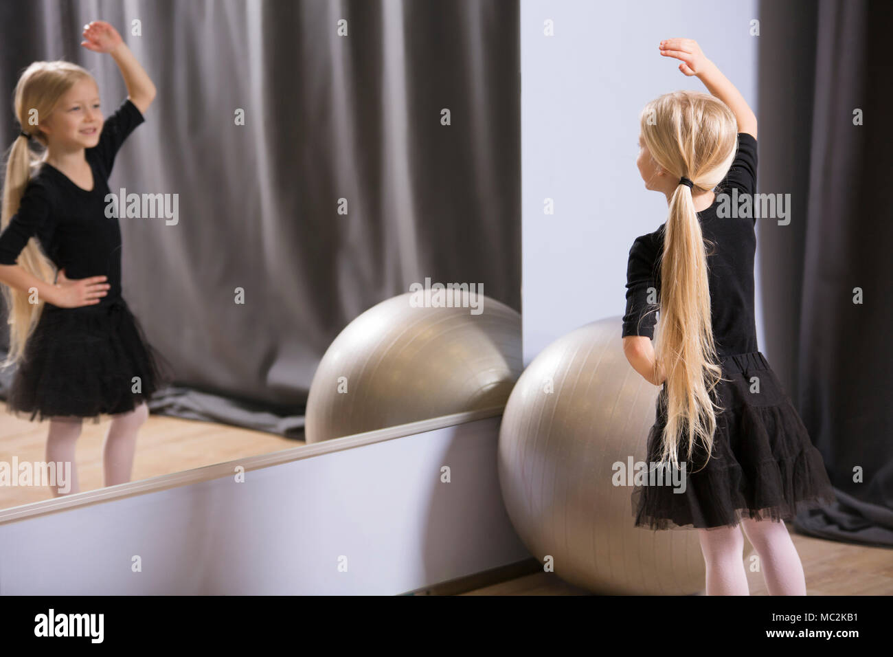 Blonde girl dancing in front of the mirror during a ballet lesson for youth Stock Photo