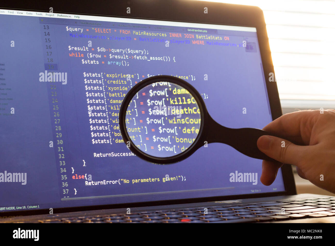 PHP back-end code zoomed through a magnifier. Computer programming source code lookup. Abstract screen of web developer. Code is created by myself. Stock Photo