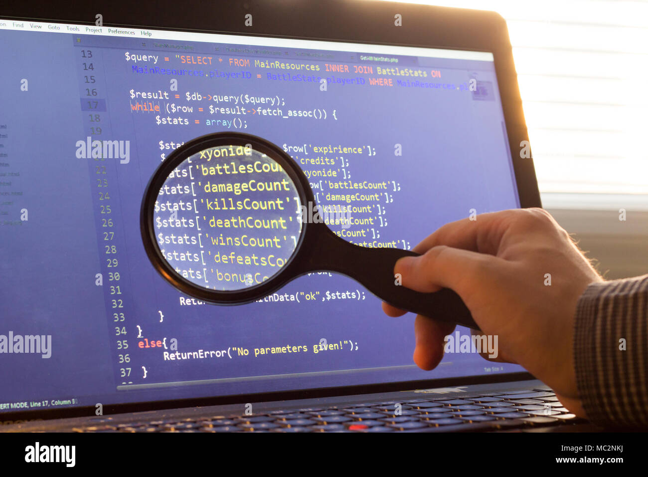PHP back-end code zoomed through a magnifier. Computer programming source code lookup. Abstract screen of web developer. Code is created by myself. Stock Photo