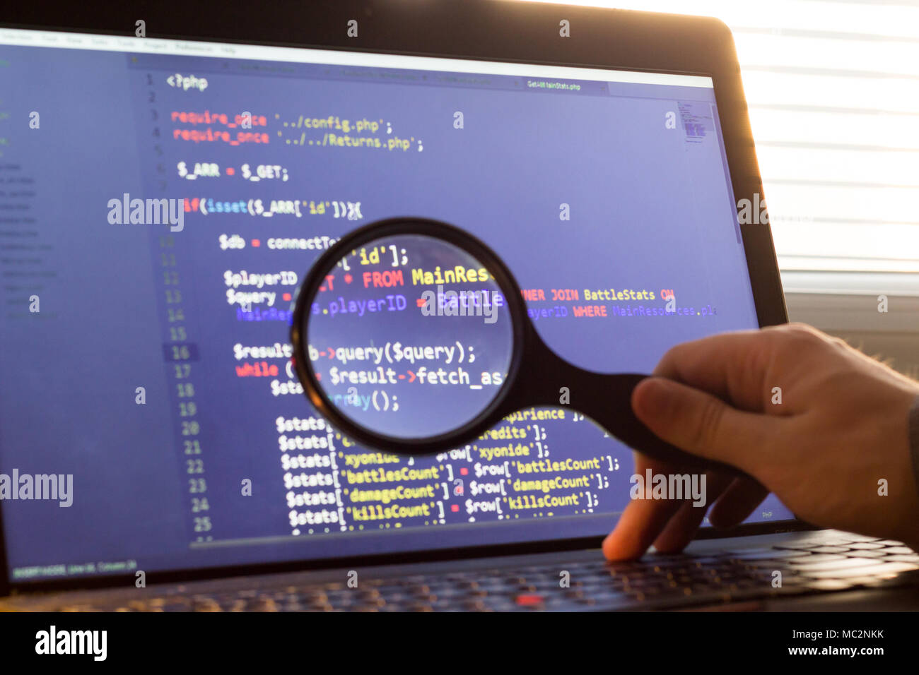 PHP back-end code zoomed through a magnifier. Computer programming source code lookup. Abstract screen of web developer. Code is created by myself. Stock Photo
