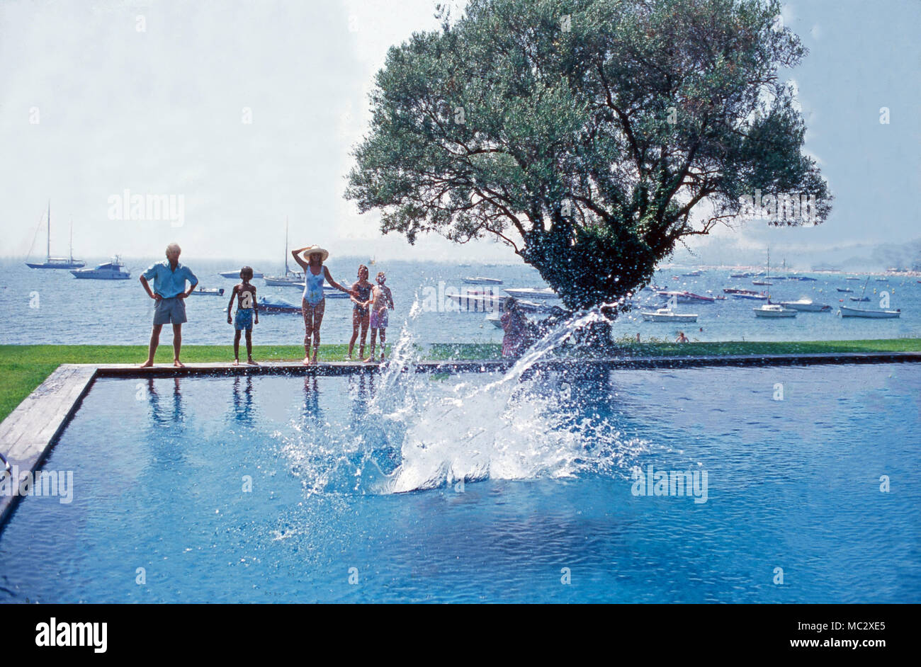 Familie Sachs hat Spaß, wenn Vater Gunter in den Pool springt. The Sachs family having fun when father Gunter jumps into the pool. Stock Photo