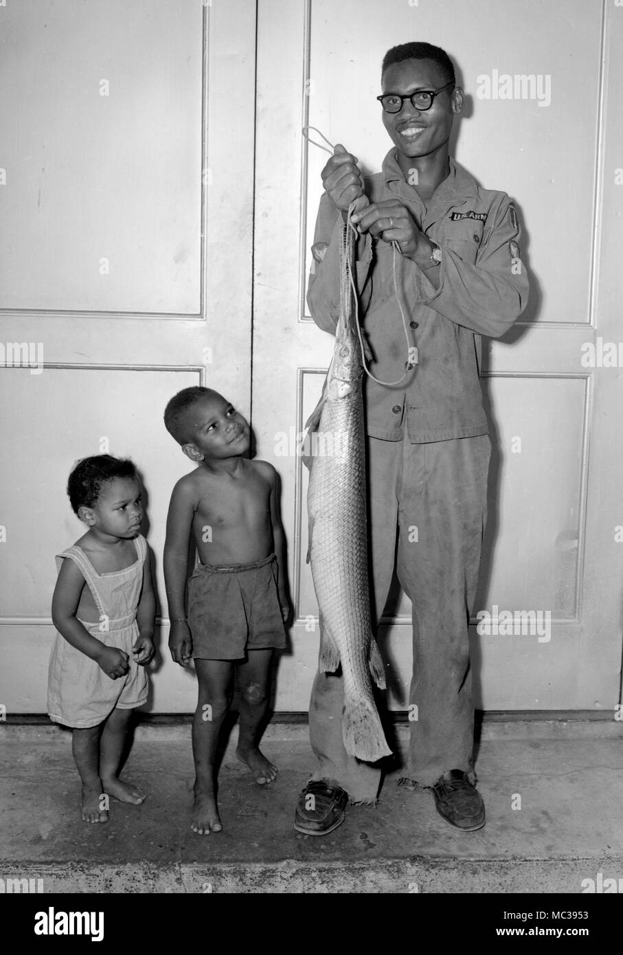 An US Army dad shows off the Alligator Gar he caught in the American South to his children, ca. 1961. Stock Photo