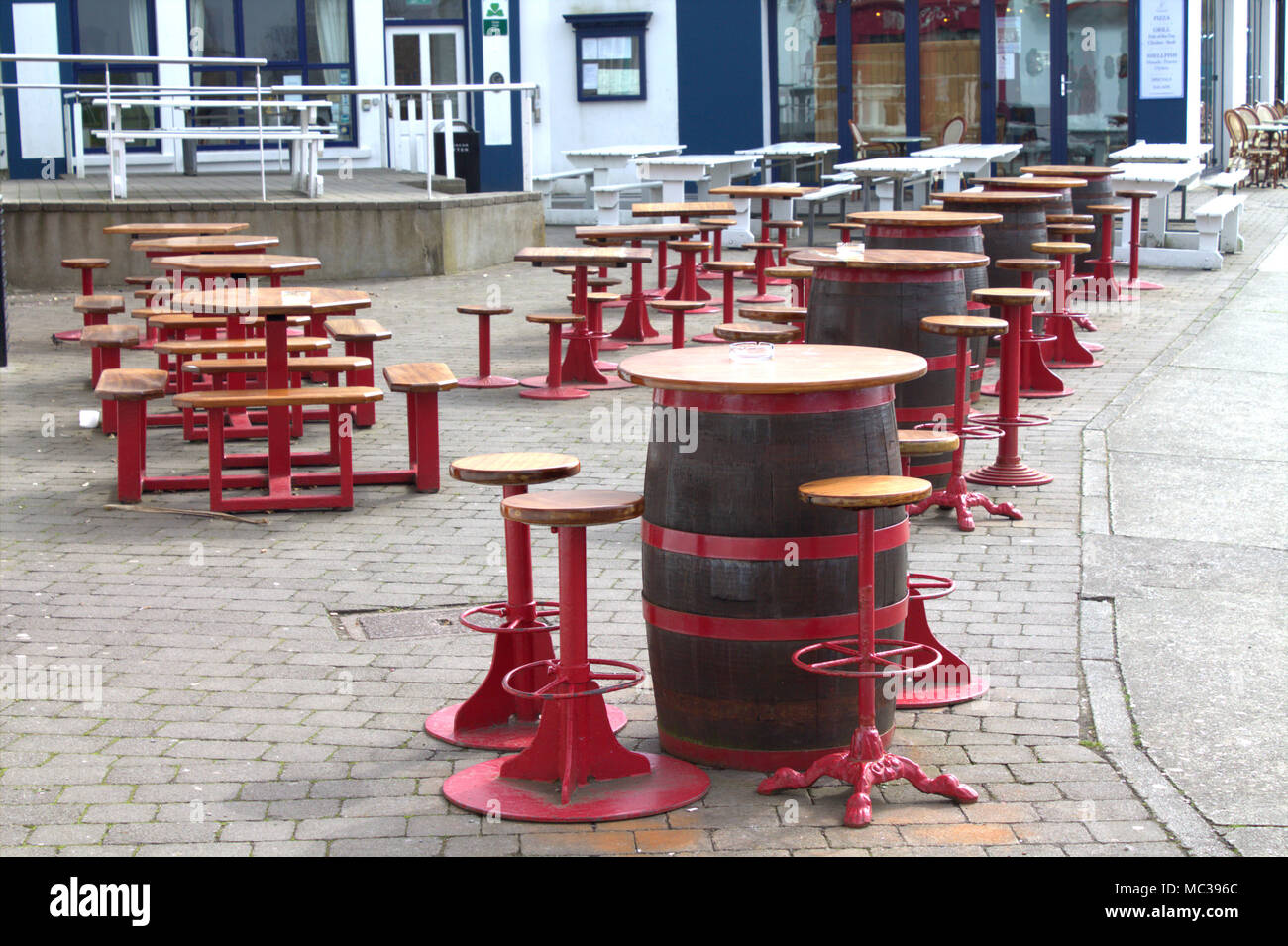 tables and chairs made up of barrels set up waiting for customers outside the pubs and restaurants of baltimore, west cork, ireland. Stock Photo