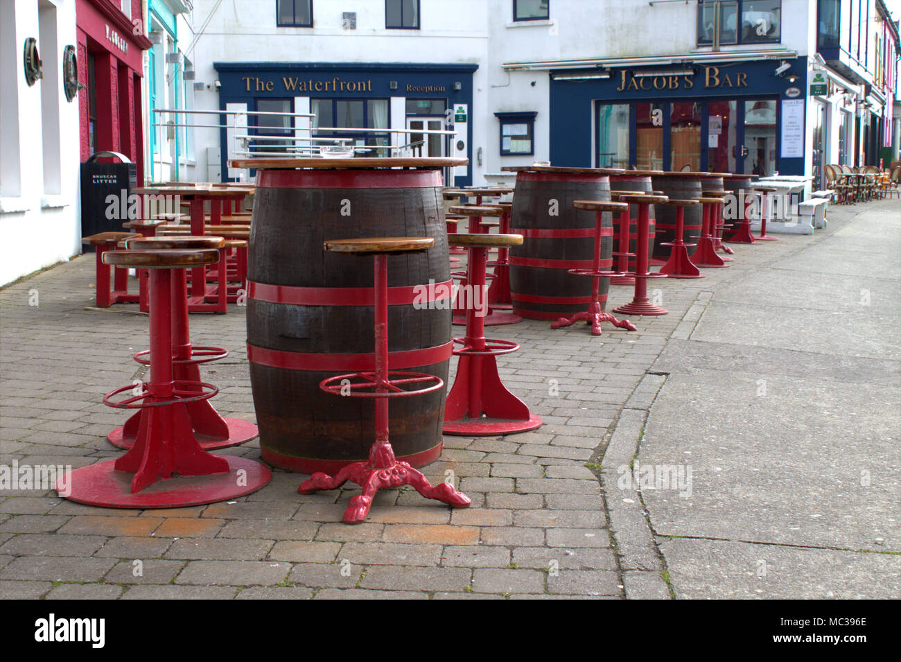 tables and chairs made up of barrels set up waiting for customers outside the pubs and restaurants of baltimore, west cork, ireland. Stock Photo