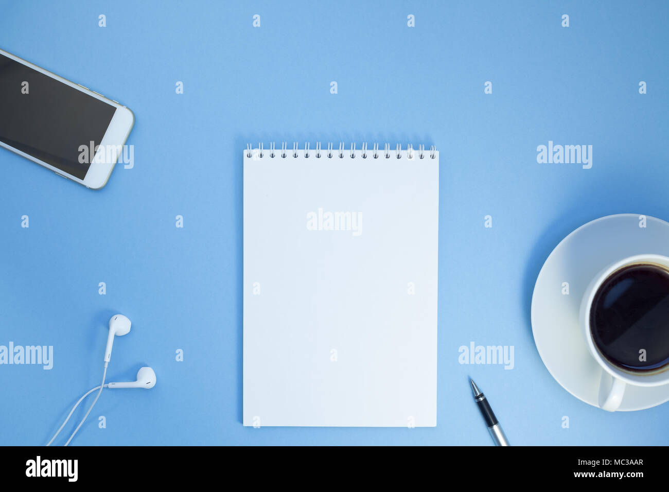 Creative flat lay photo of workspace desk with paper notebook, smartphone, earpieces, pen and coffee with copy space background minimal style Stock Photo