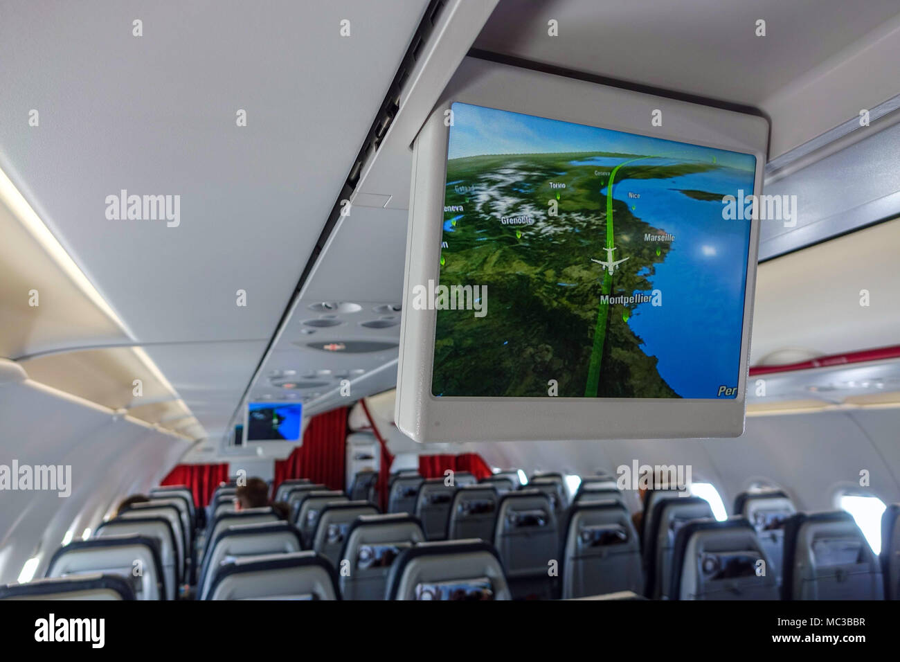 On board quiet Aegean Airlines Airbus A320 with TV screens showing flight progress Stock Photo