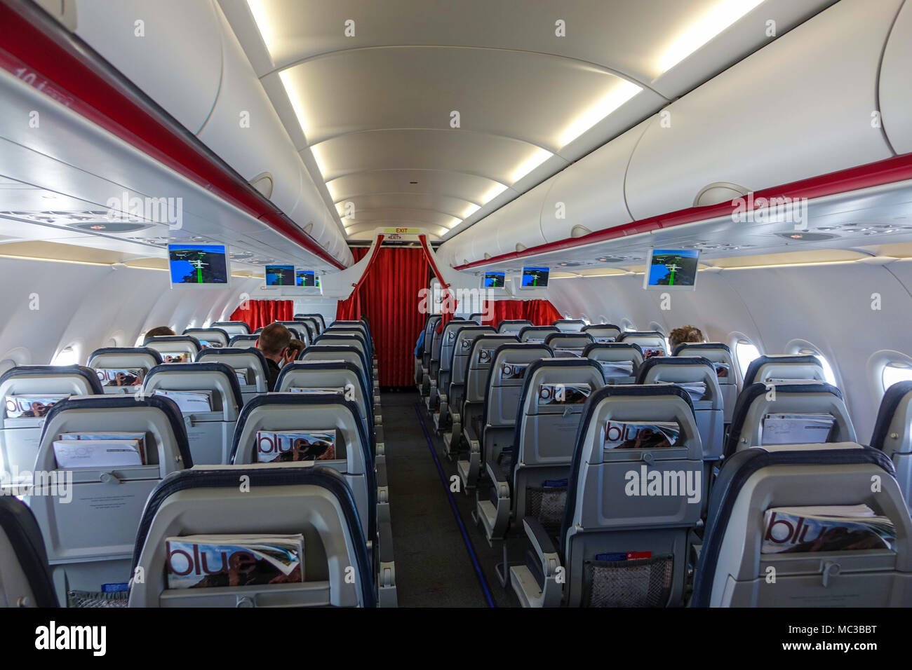 On board quiet Aegean Airlines Airbus A320 with TV screens showing flight progress Stock Photo