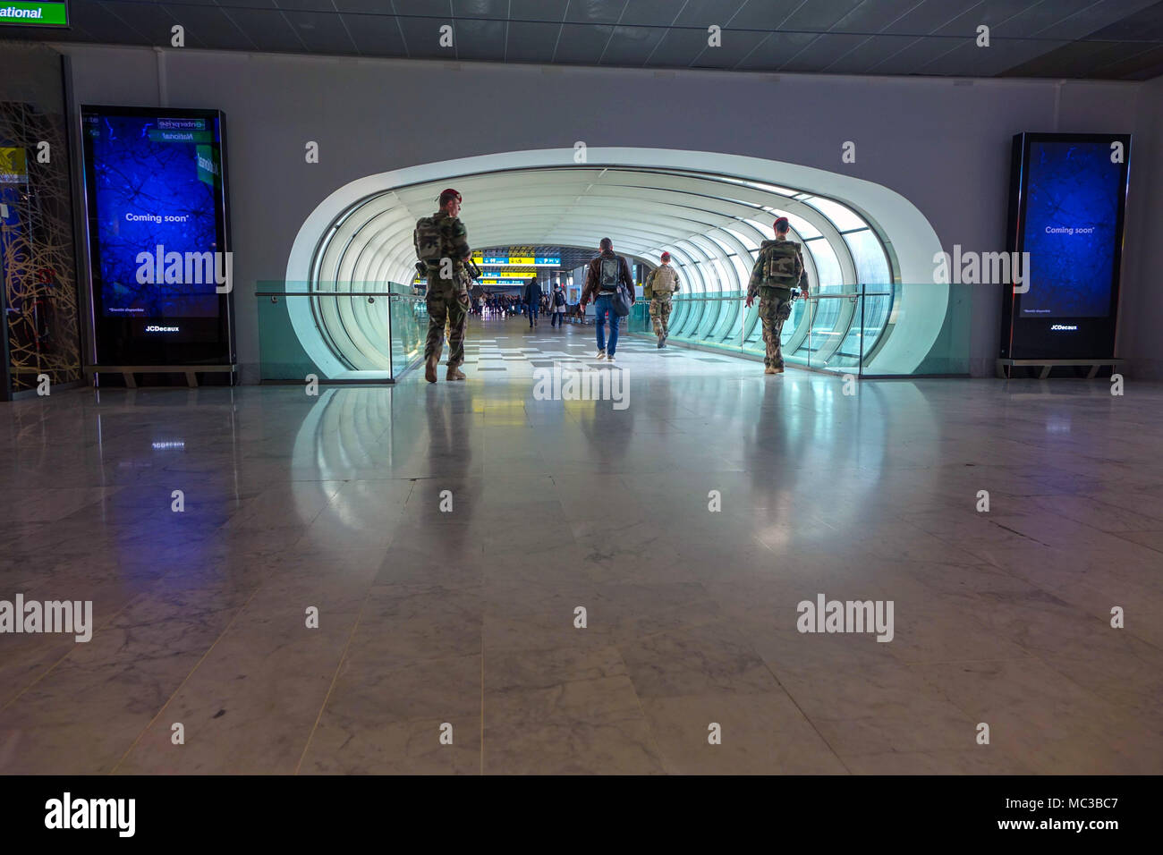 Pedestrian tunnel with four soldiers walking through, Toulouse Blagnac airport, France Stock Photo