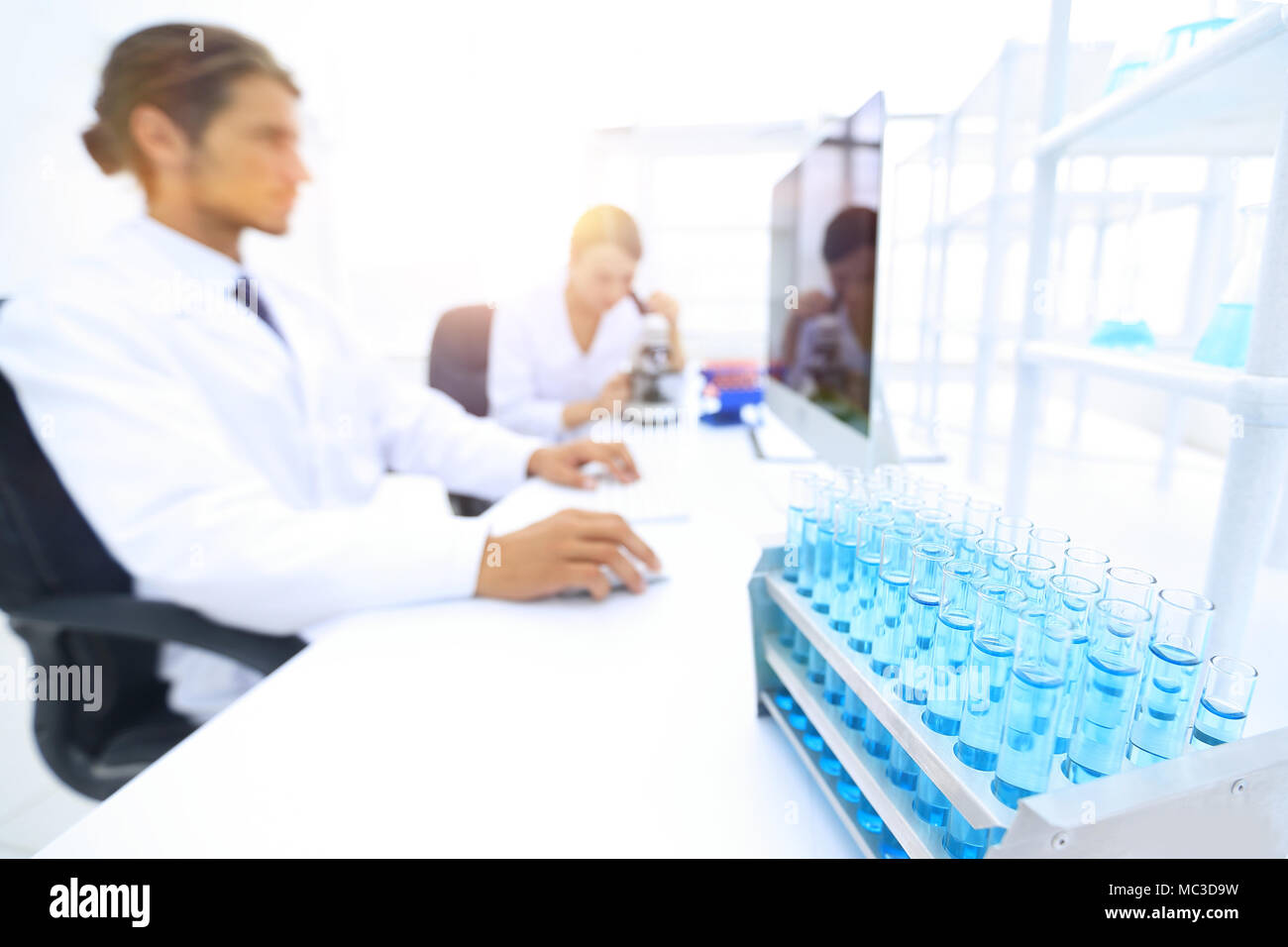 Male And Female Scientists Using Microscopes In Laboratory Stock Photo