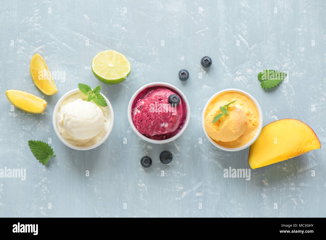 Three various fruit and berries ice creams on blue background, copy