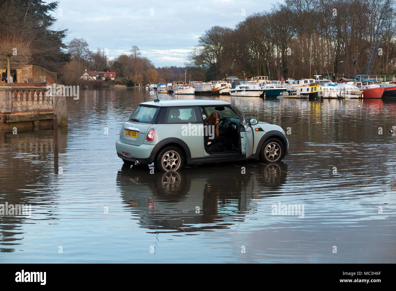Motorist / Mini car driver cuts it fine in quickly rising water as Spring Tide on the Thames threatens to overwhelm and flood her car. (96) Stock Photo