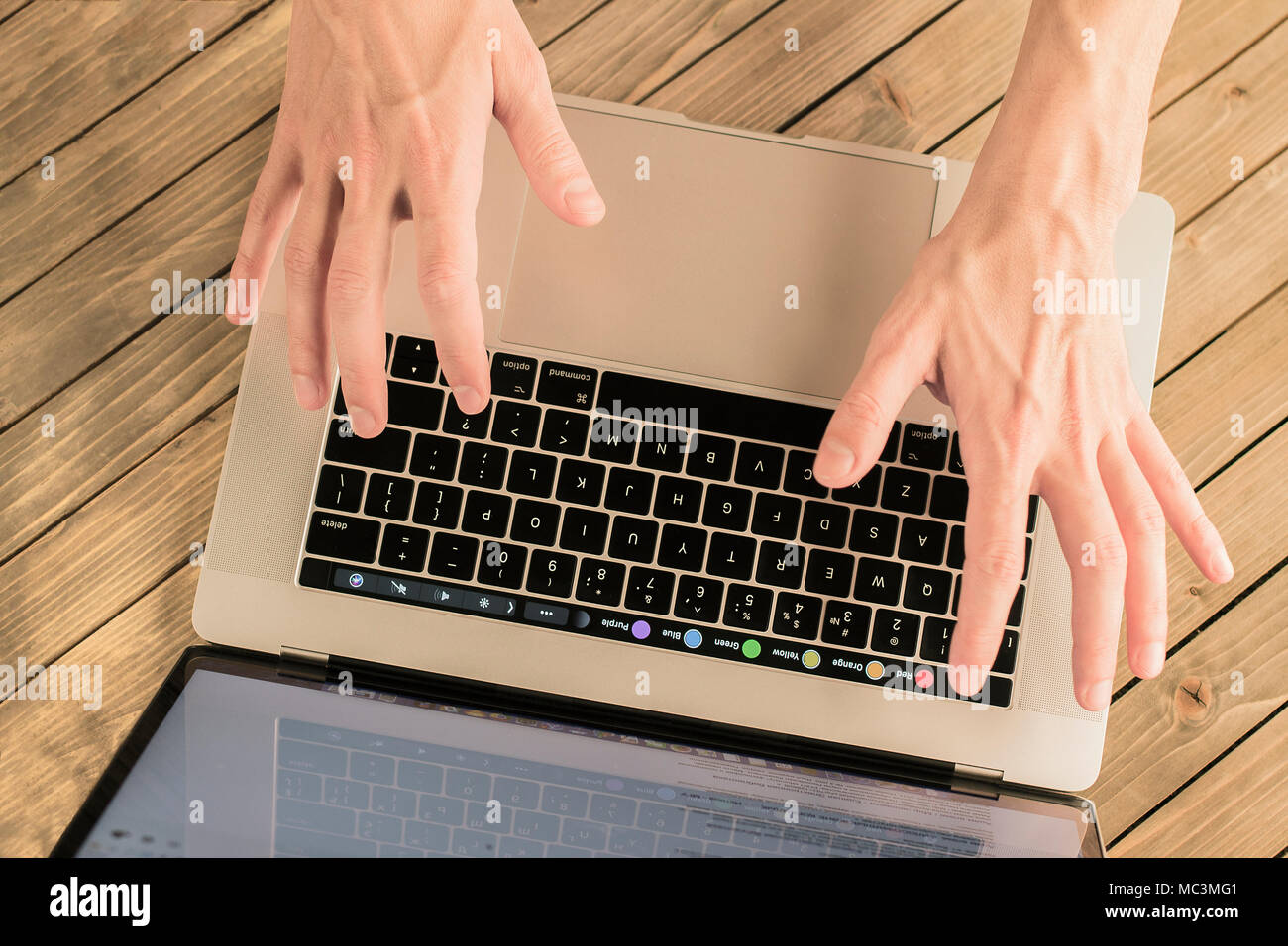 Male hands on the keyboard. Up view of male hands typing on the MacBook keyboard. Stock Photo