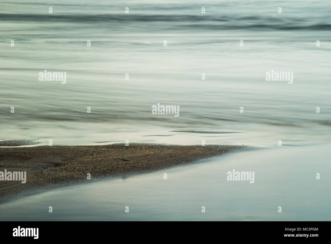 Abstract photo of a spit of sand protruding into the sea with a slow shutter speed Stock Photo