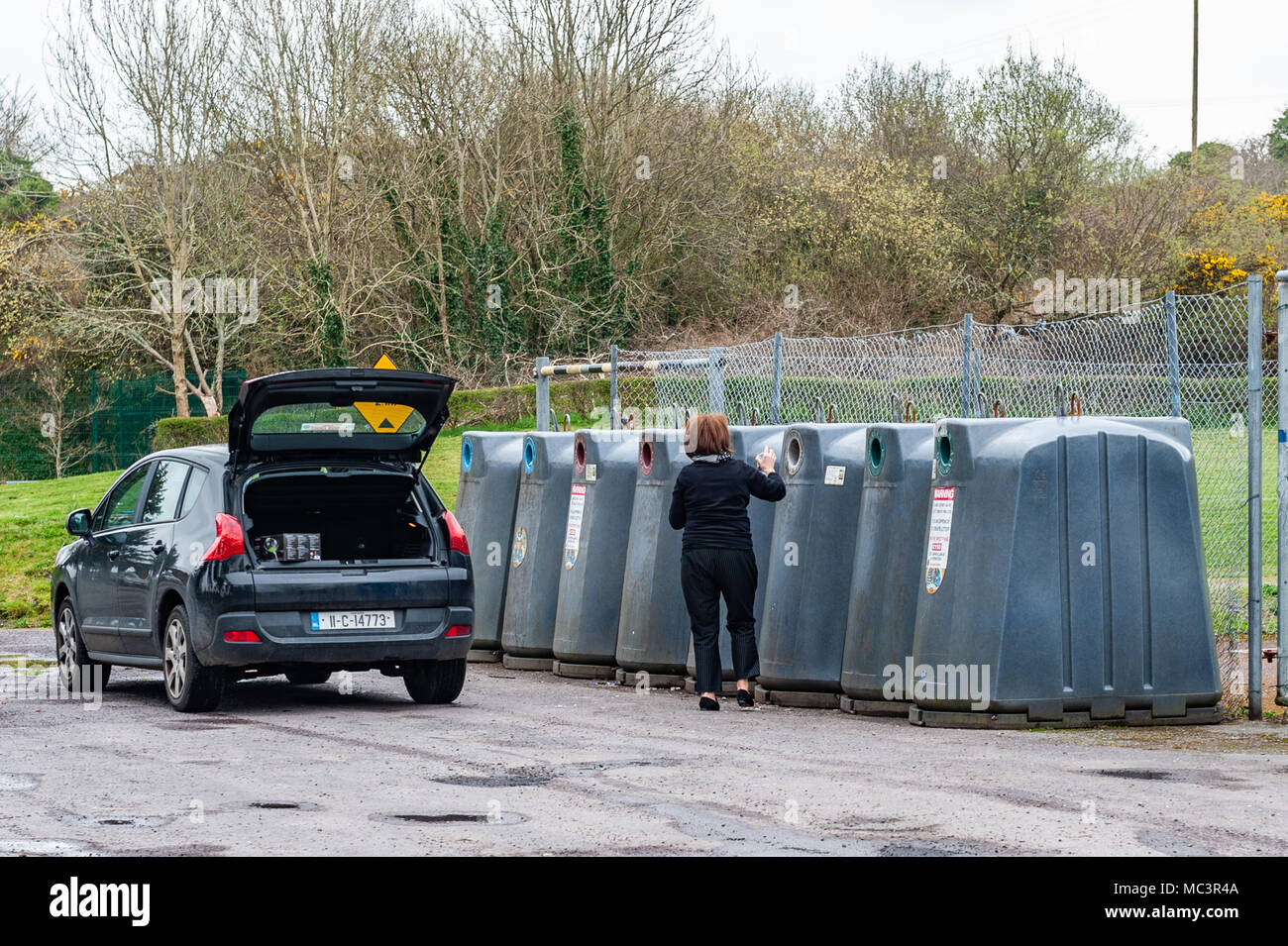 Woman recycling various types of bottles and cans at Ballydehob