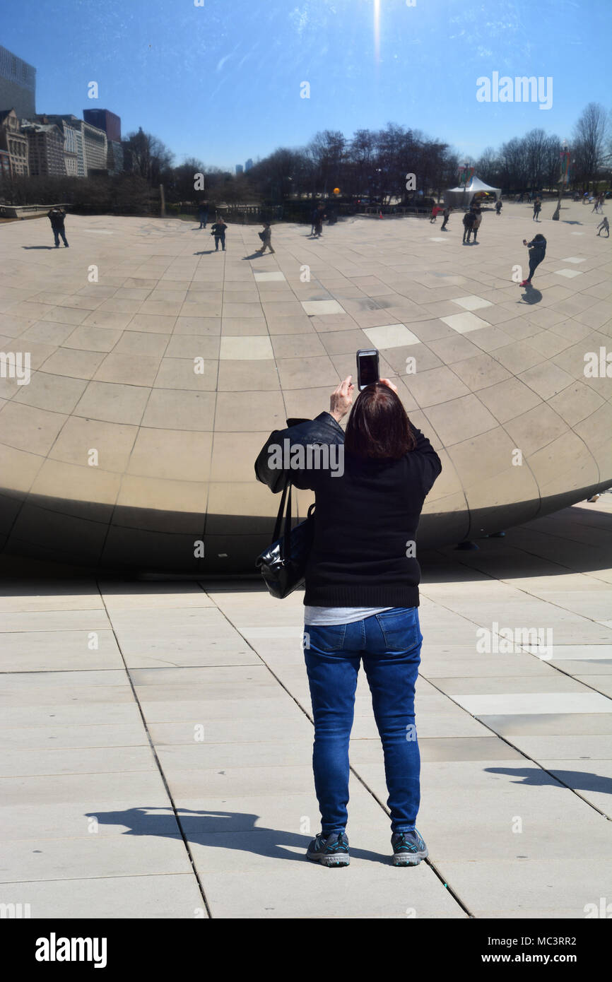 A woman takes a selfie with Chicago's 'Bean' in Millennium Park on a warm spring day. Stock Photo