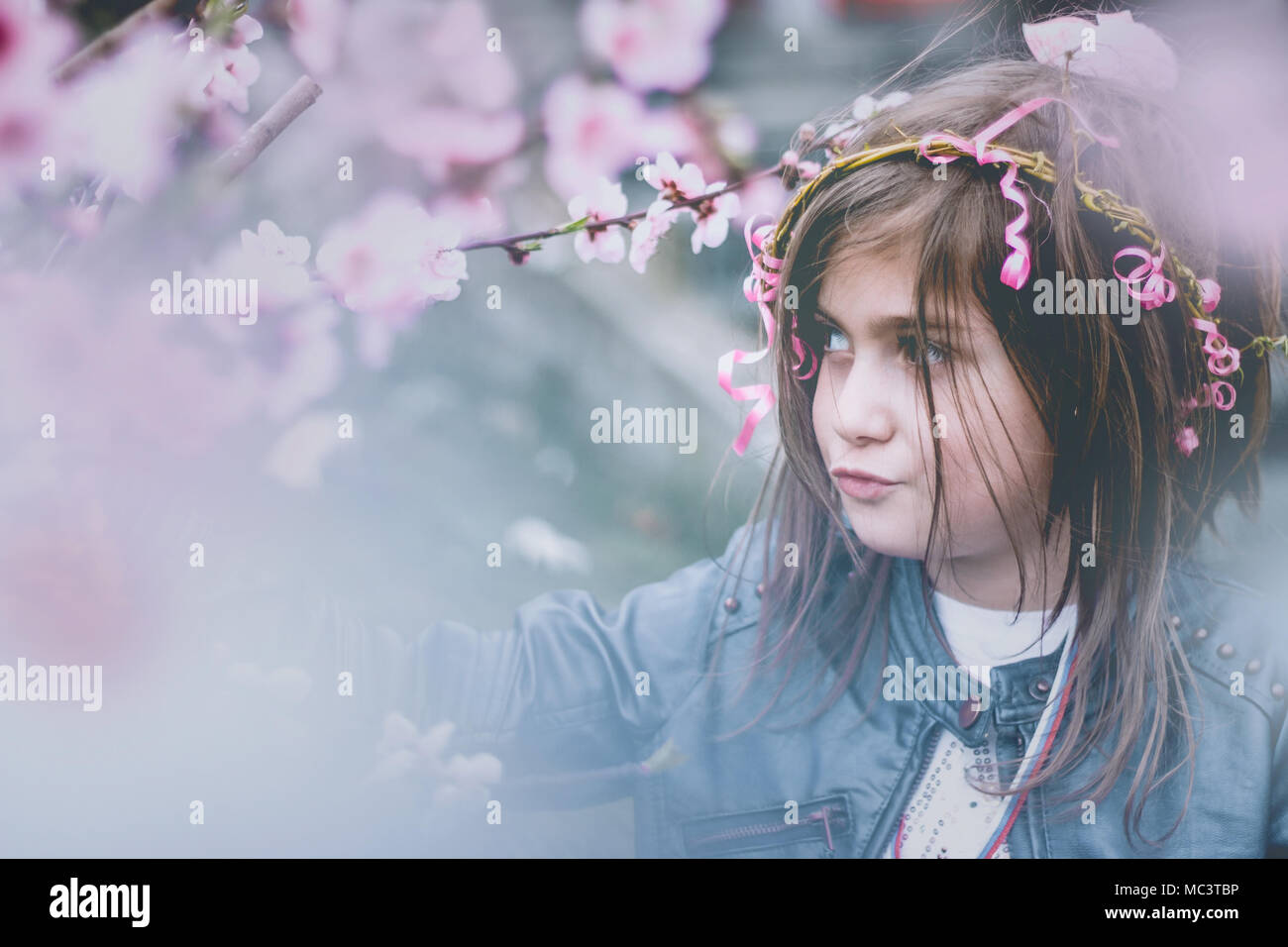 Beautiful little girl with flower wreath on her hair, traditionally wore for Lazarus saturday, among cherry flowers; spring background Stock Photo