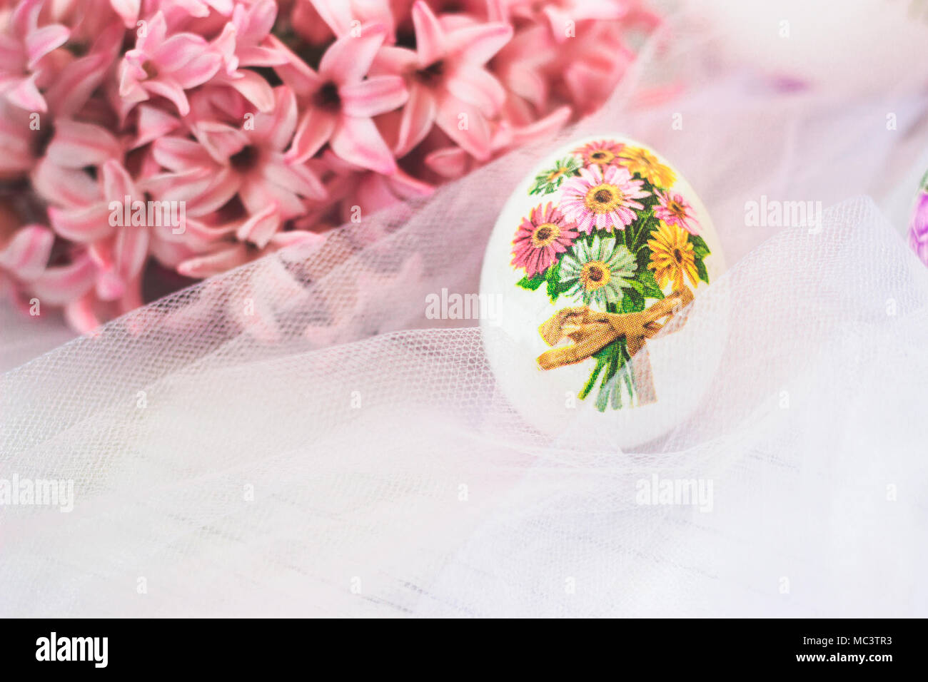 Decoupage decorated Easter egg, with pink hyacinths flowers, on white tulle background Stock Photo