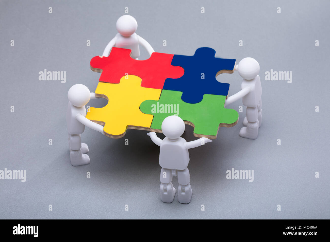 High Angle View Of Human Figures Solving Multi Colored Jigsaw Puzzles Stock Photo