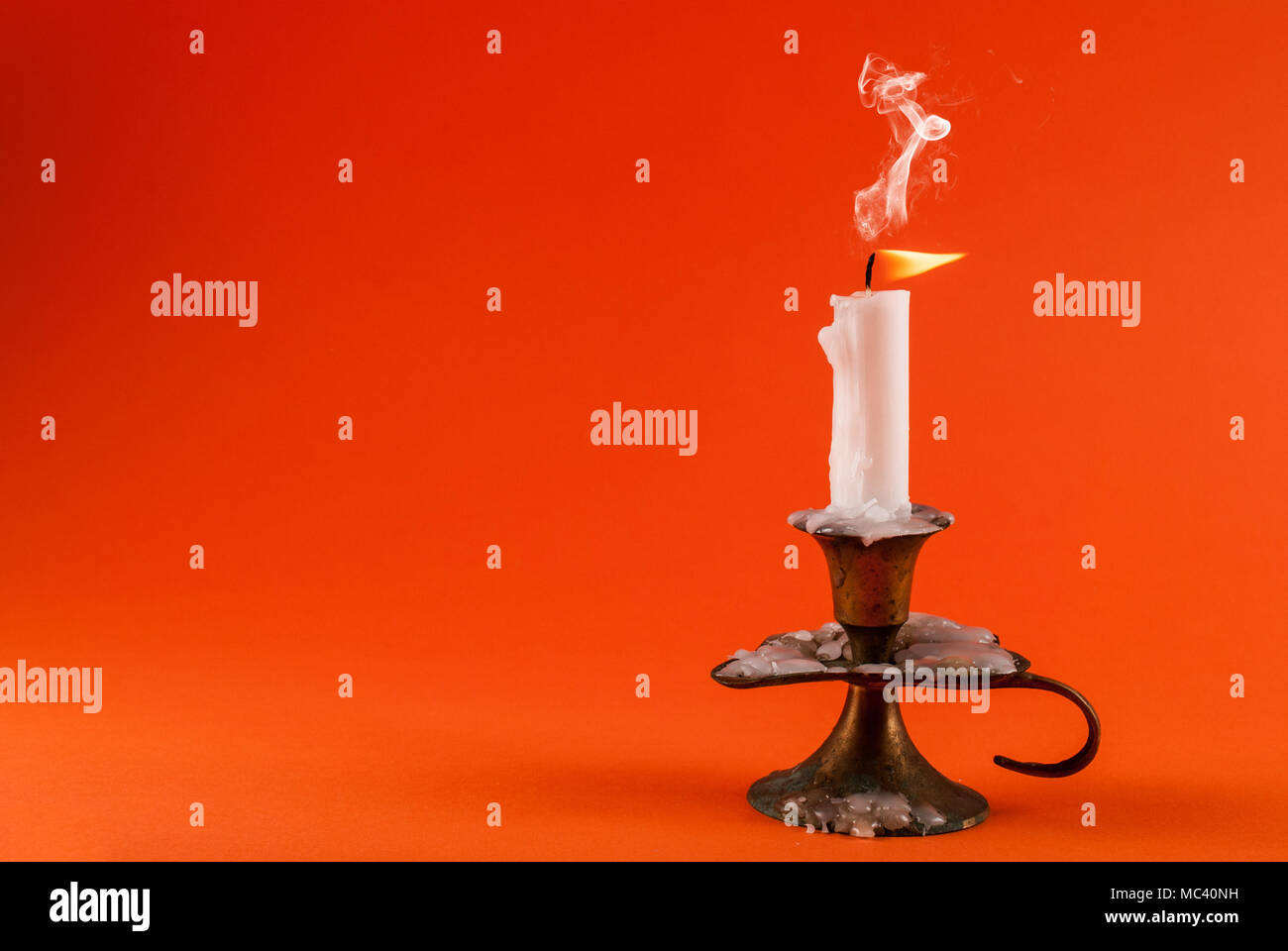 Candle is smoky in old candlestick isolated on orange background. Space