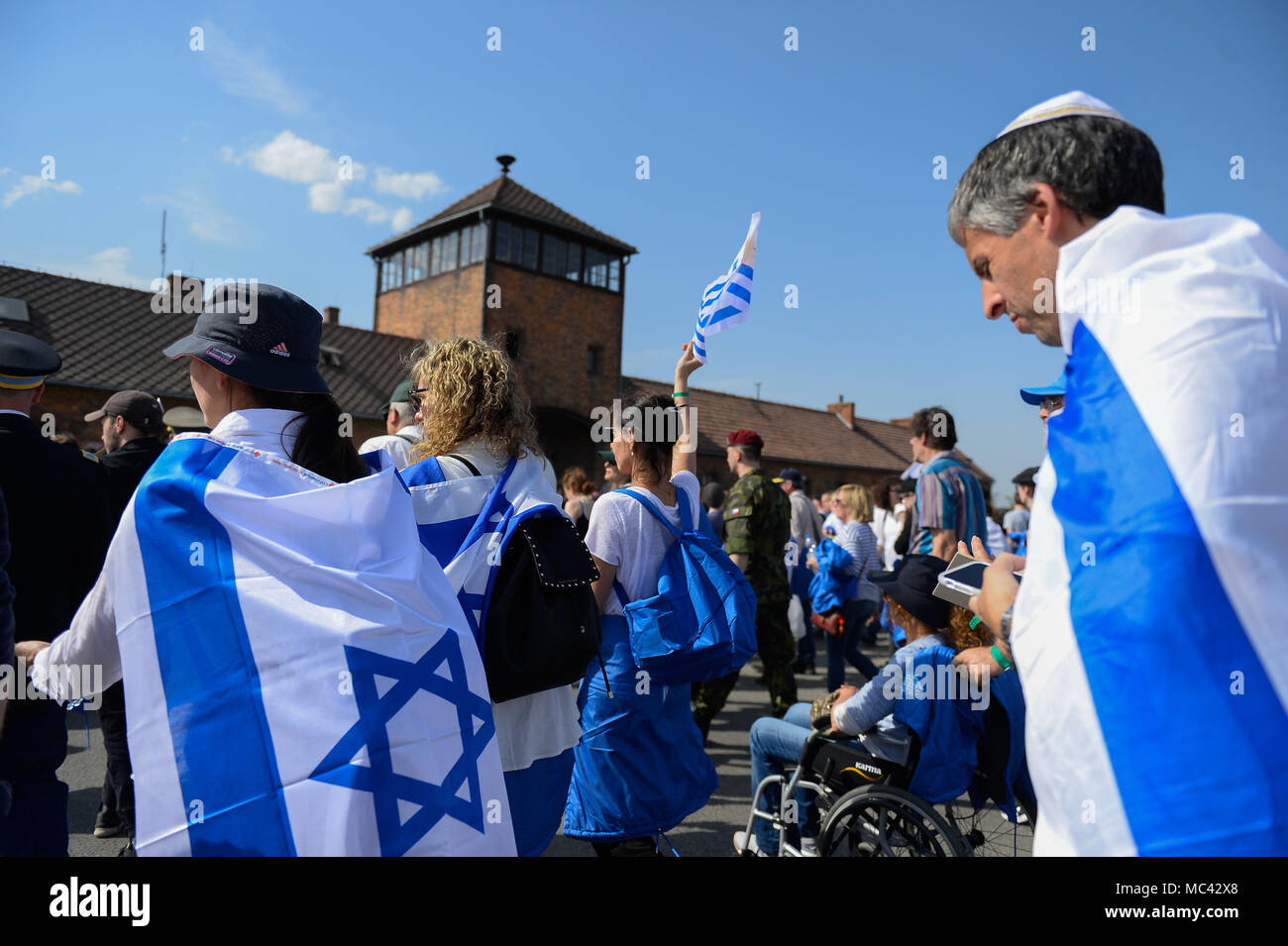 Participants wave Israeli flags at the main gate of the former Nazi German Auschwitz-Birkenau death camp during the 'March of the Living' at Oswiecim. The annual march honours Holocaust victims at the former Nazi German Auschwitz-Birkenau death camp in southern Poland. Stock Photo
