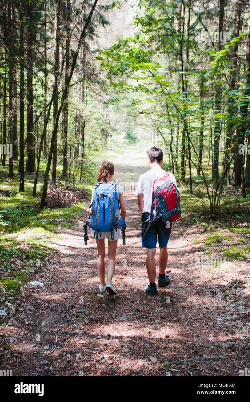 Young boy and girl wandering in a forest on summer day equipped with backpacks Stock Photo