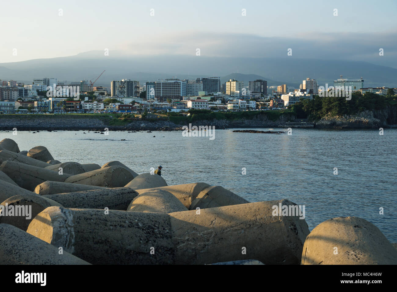 Cityscape with wavebreakers of Seogwipo with mount Hallasan in background, Jeju Island, South Korea Stock Photo