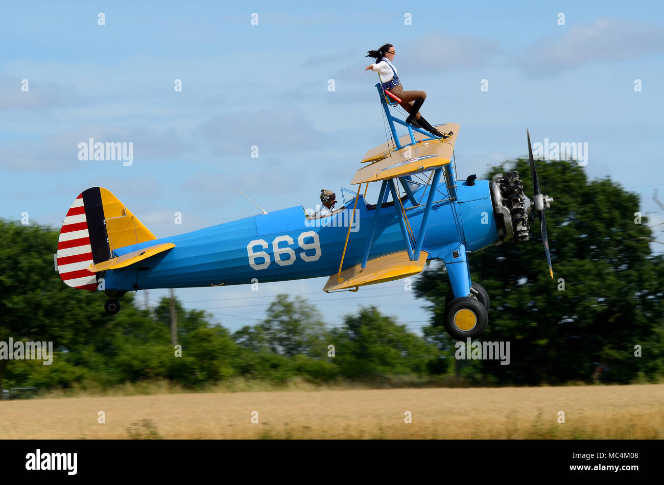 Sarah Niles wingwalking on a Boeing Stearman at Damyns Hall Aerodrome with Aerobatic Tactics. Girl on the wing, wing walking. Close to ground Stock Photo