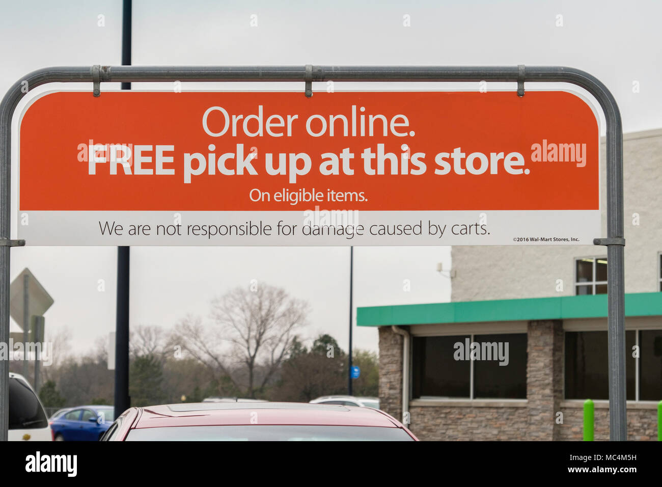 A sign above a shopping cart caddy in a Walmart parking lot advertising Ordering online, picking up at store. Wichita, Kansas,USA. Stock Photo