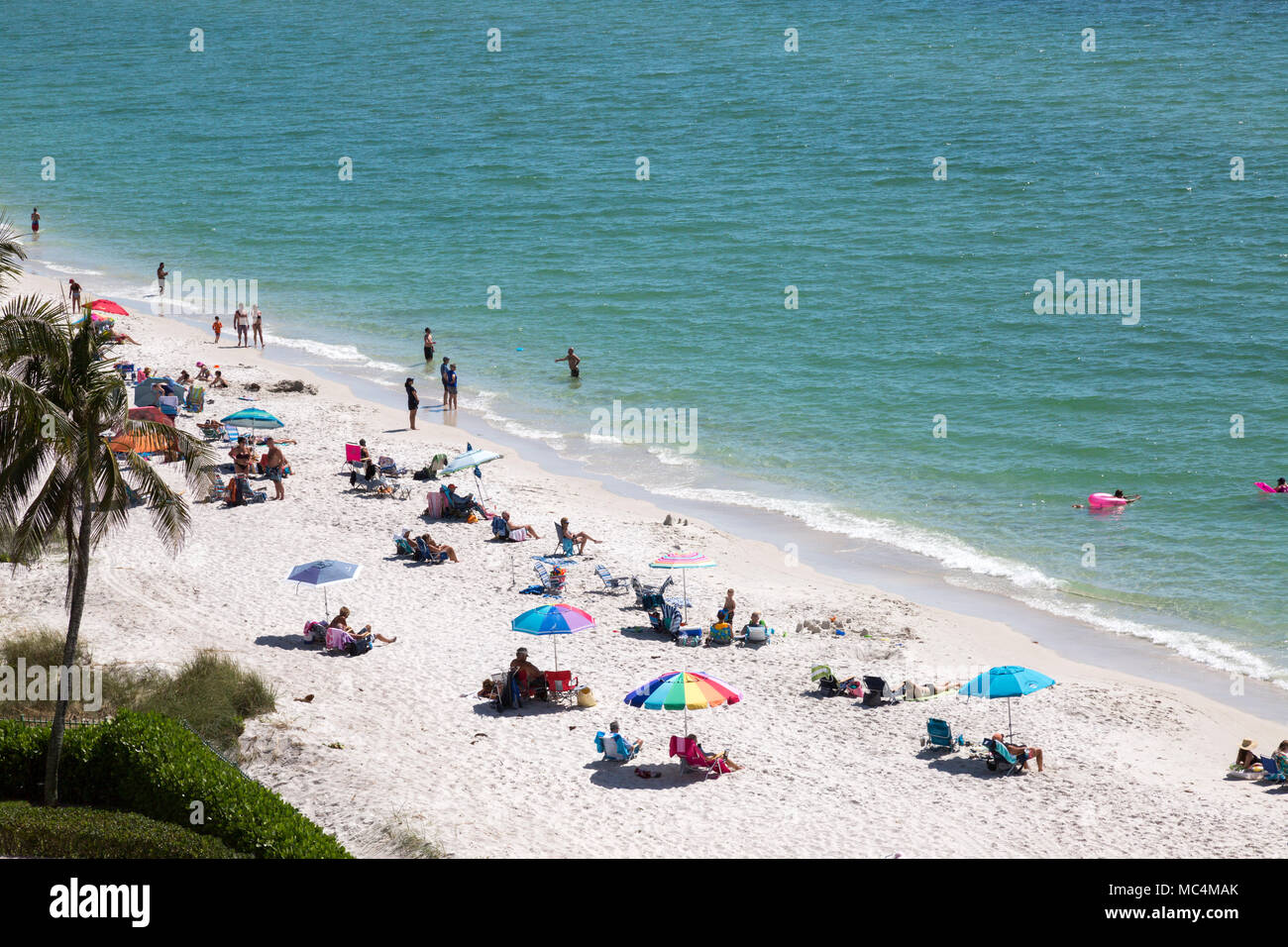 View from above of beach scene along the coast of Florida in Naples. Families vacationing over spring break. Colorful beach umbrellas. Stock Photo