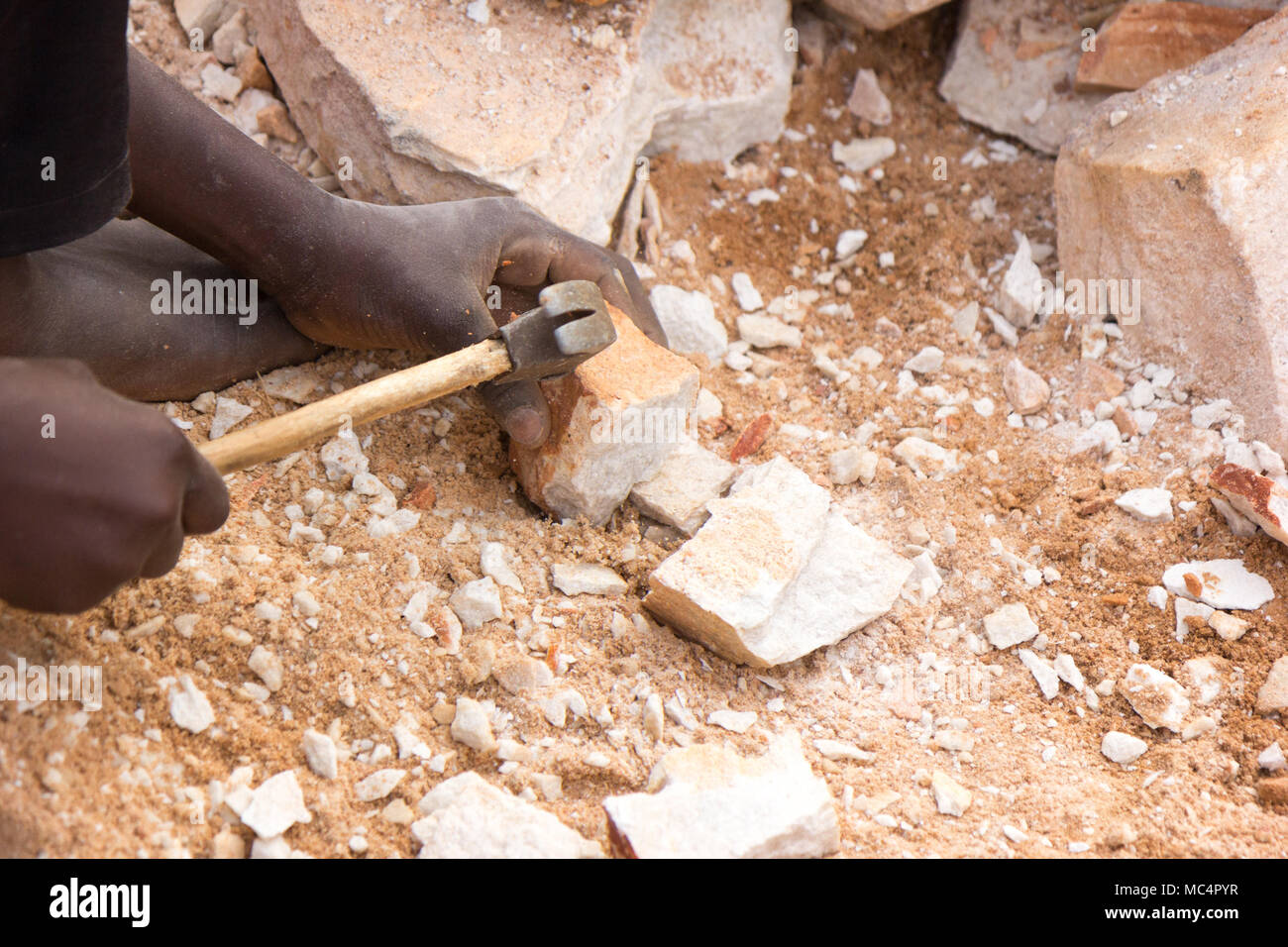 Ugandan child's hands breaking rocks into small slabs for his or her ...