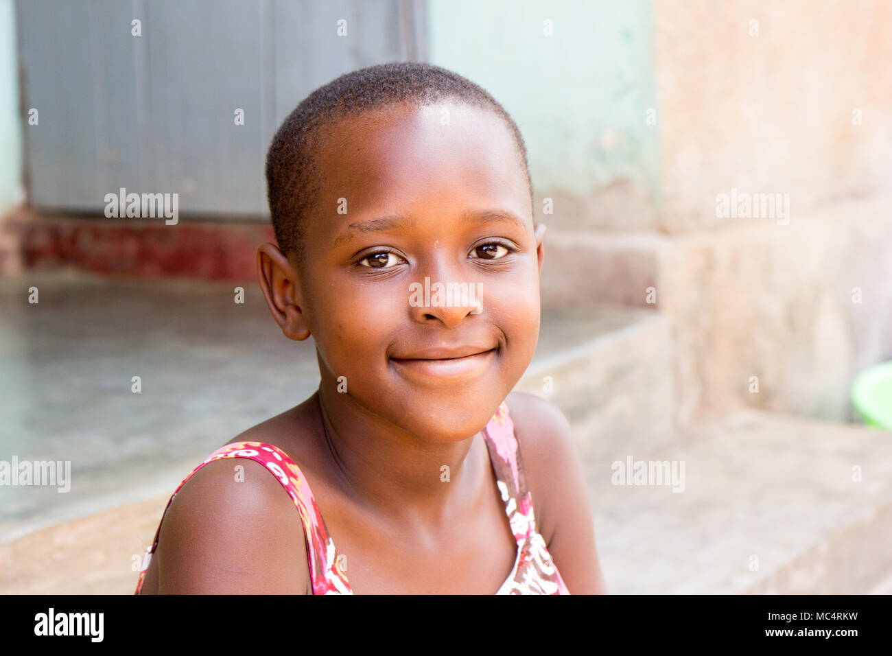 Lugazi, Uganda. 14 May 2017. A portrait of a beautiful Ugandan girl sitting on the stairs in front of a house. Stock Photo
