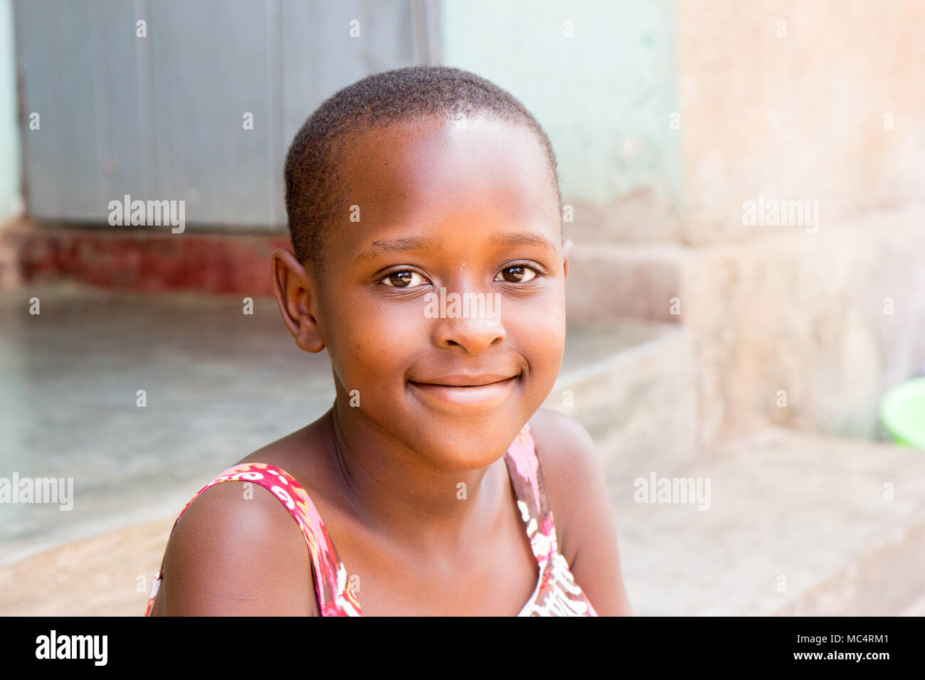 Lugazi, Uganda. 14 May 2017. A portrait of a beautiful Ugandan girl sitting on the stairs in front of a house. Stock Photo