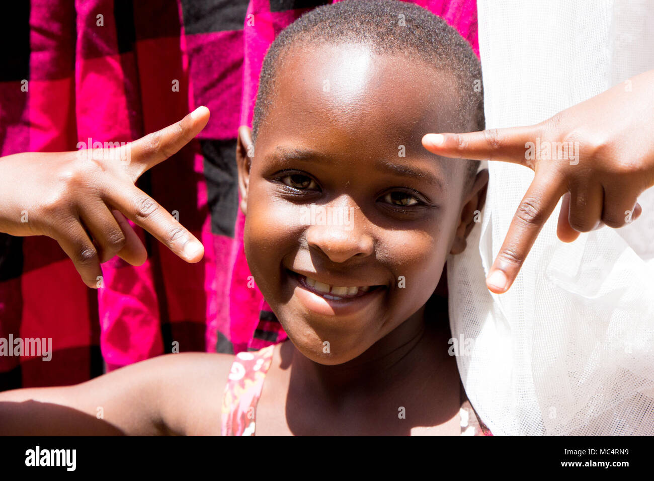 Lugazi, Uganda. 14 May 2017. A portrait of a beautiful Ugandan girl among drying laundry. Stock Photo