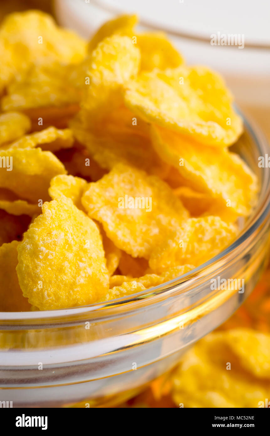 Ingredients for breakfast. Defocused and blurred image of dry corn flakes in a transparent bowl closeup with shallow depth of focus Stock Photo