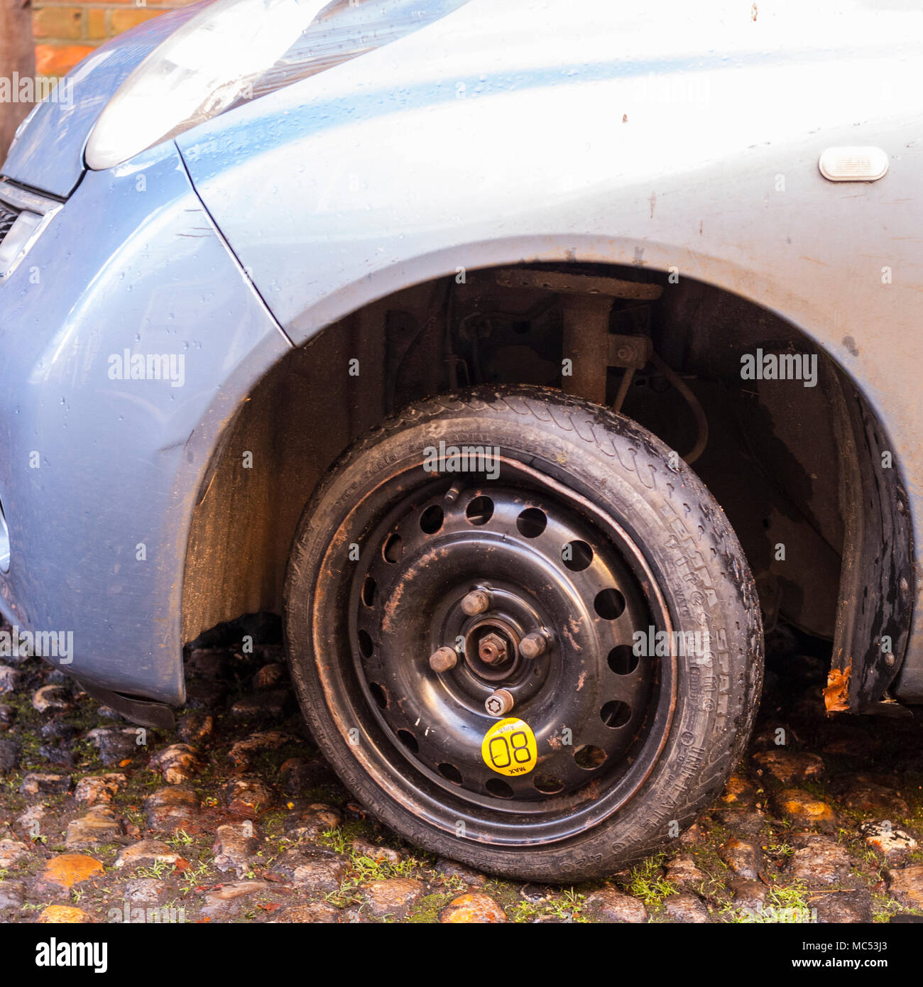A cheapy skinny spare wheel fitted to a car Stock Photo