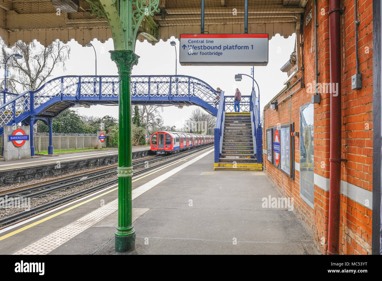 Barkingside, Ilford, Essex, UK - April 6, 2018:  Shot of the platform with a passenger on the footbridge of tube station with train departing. Stock Photo