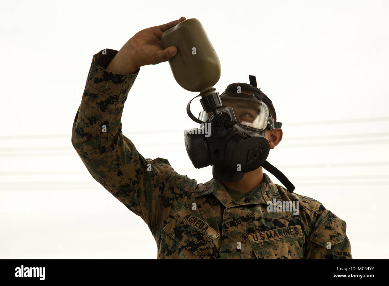 U.S. Marine Corps Cpl. Joshua Agreda, a supply noncommissioned officer assigned to the 13th Marine Expeditionary Unit, demonstrates how to properly drink from a canteen while wearing the M50 Joint Service General Purpose Mask (JSGPM) at the 43 Area Gas Chamber facility, Camp Pendleton, California, Jan. 30, 2018.  Marines are required to receive Individual Protective Equipment Confidence training annually, which includes the proper fitting, maintenance and employment of the gas mask.  (U.S. Marine Corps photo by Gunnery Sgt. Jon Spencer) Stock Photo