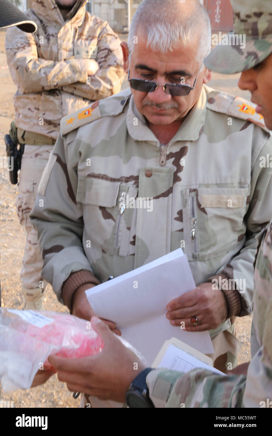 An Iraqi army officer receives oral airway devices during a delivery of medical equipment to the Iraqi army at the Besmaya Range Complex, Iraq, Jan. 28, 2018.  U.S. Army Sgt. Chadwick Dile, left, and 1st Lt. Grisel Davila, center, both assigned to the 536th Support Maintenance Company, 275th Combat Sustainment Support Battalion, display a mannequin to an Iraqi army leader during a medical equipment transfer at the Besmaya Range Complex, Iraq, Jan. 28, 2018.  The U.S. provides training and equipment to vetted Iraqi security forces through the National Defense Authorization Act FY 2015; Iraq Tra Stock Photo