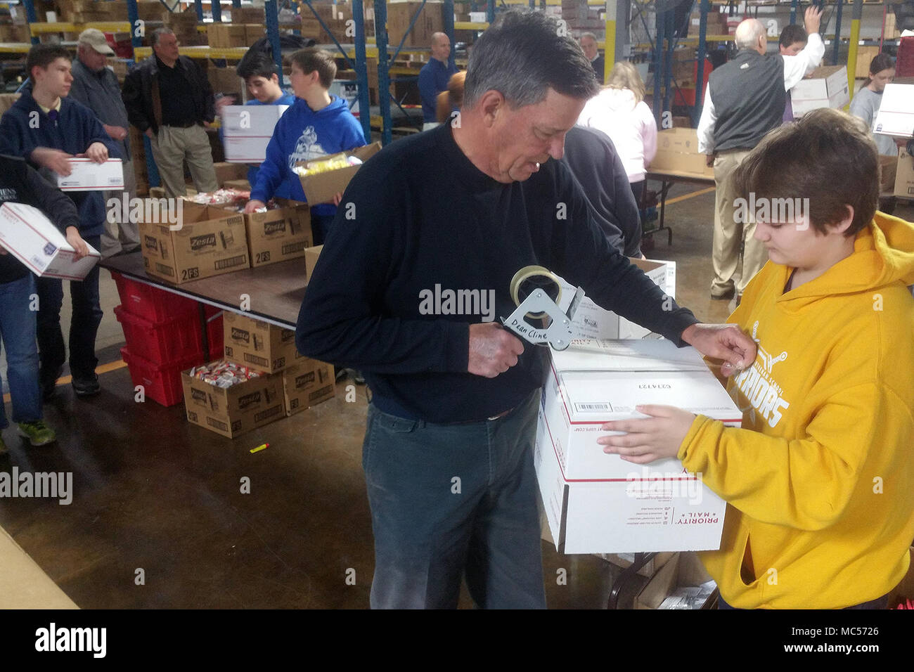 Students from St. Stephens Lutheran School turn donated goodies from North Carolina businesses into care packages at Hackney Service Merchandisers in Hickory, North Carolina for deployed North Carolina National Guard Soldiers via the NCNG Soldiers & Airmen Assistance Fund, Jan. 31, 2018. Members of Soldiers and Airmen Fund and retired NCNG leaders Air National Guard Col. Steven Martin and Army National Guard Sgt. Maj. Dennis Roach and Col. Drew Goodwin helped plan the event with Hickory businessman and retired Army Reserve Command Sgt. Maj. Dean Cline Sr. Hackney provided storage space for the Stock Photo